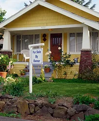 yellow craftsman house with "for sale by owner" sign in front